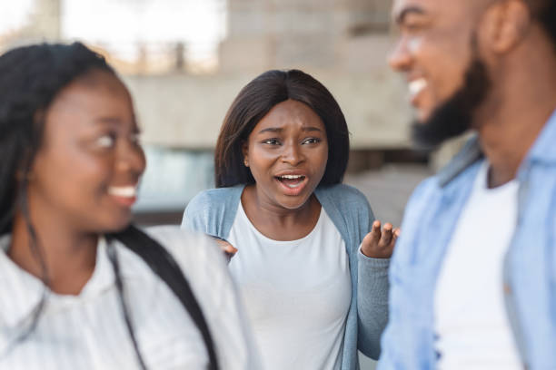 Grumpy black girl angry to her boyfriend flirting with another woman Jealousy Concept. Grumpy black girl angry to her boyfriend that flirting with another woman, standing with furious face expression on background ex girlfriend stock pictures, royalty-free photos & images