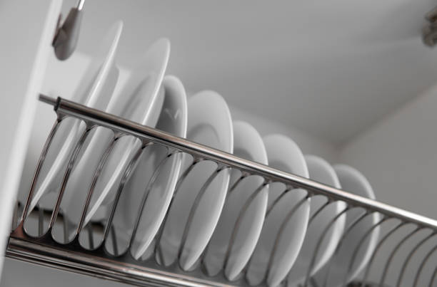 istock Dish drying metal rack with big nice white clean plates. Traditional comfortable kitchen. Open white dish draining closet with wet dishes of glass and ceramic, plates, bowls drying inside on rack. 1198617358