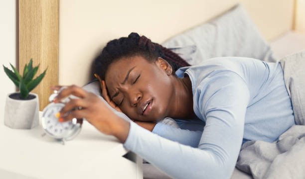 istock Woman Turning Off Alarm-Clock Touching Head Waking Up In Bed 1198617385