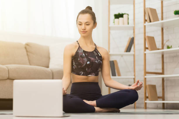 istock Online training. Woman practicing yoga and using laptop 1198620369