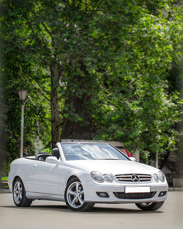 Rostov-on-Don, Russia, 06,09, 2013. White car cabriolet on a summer day next to green trees.