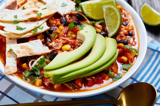 istock Chicken Taco Soup with black bean, corn kernels, topped with tortilla strips, avocado slices and lime 1198620807