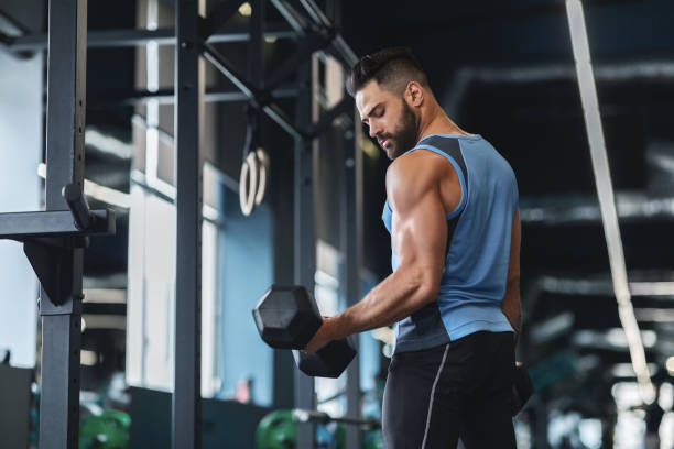 istock Handsome athlete training arms with dumbbells at gym 1198621387