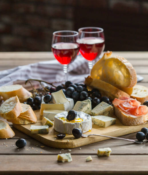 istock Assorted cheeses on wooden board. Camembert, cheese with blue mildew, gouda, hard cheese, grape, red wine 1198622469