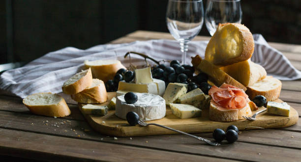 istock Assorted cheeses on wooden board. Camembert, cheese with blue mildew, gouda, hard cheese, grape, red wine 1198622501