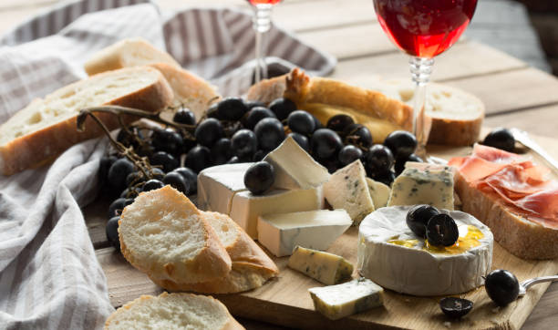 istock Assorted cheeses on wooden board. Camembert, cheese with blue mildew, gouda, hard cheese, grape, red wine 1198622514