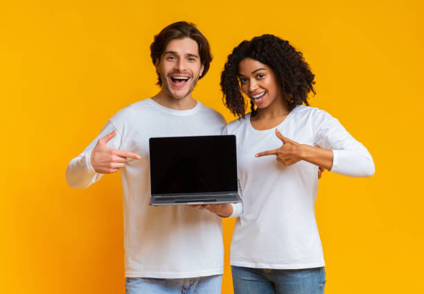 istock Smiling multiracial couple pointing at laptop with black screen 1198622804