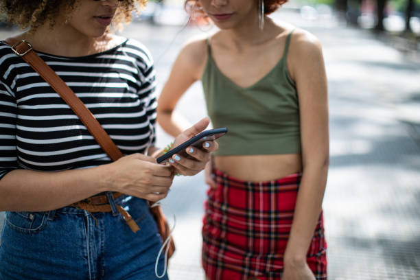 istock Two young women having fun sharing music on the street 1198623091