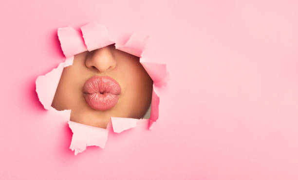 femme faisant la moudre les lèvres lumineuses dodues, peep dans la fendu du papier - sexy lips photos et images de collection