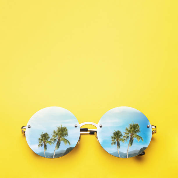 istock Palm trees and mountains are reflected in sunglasses on a yellow background. Vacation and travel concept with copy space 1198625351