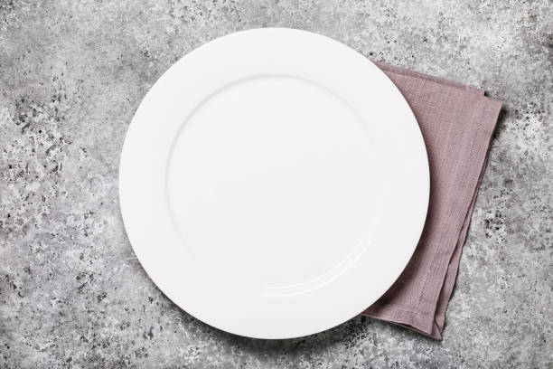 istock Empty white plate with a napkin on a table with concrete texture, top view. Food background 1198625362