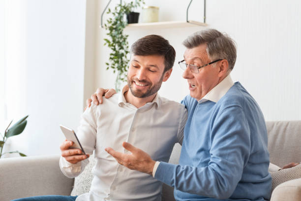 istock Adult Son Teaching Elderly Father To Use Cellphone At Home 1198629121