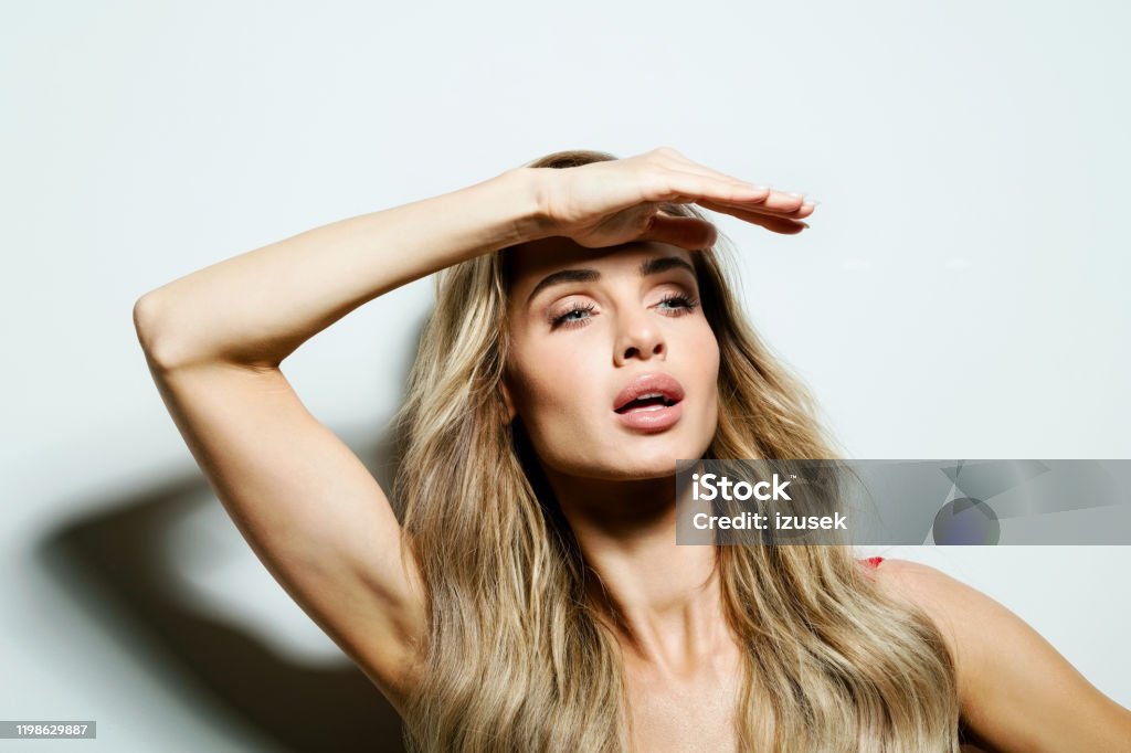 Glamour portrait of beautiful young woman Summer portrait of happy beautiful long hair young woman, looking away with raised hands. Studio shot on white background. Human Face Stock Photo