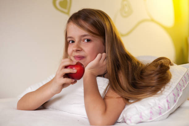 istock Young girl eating an apple in bed 1198629945