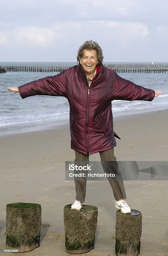 Senior donna su una spiaggia a piedi - Foto stock royalty-free di Adulto