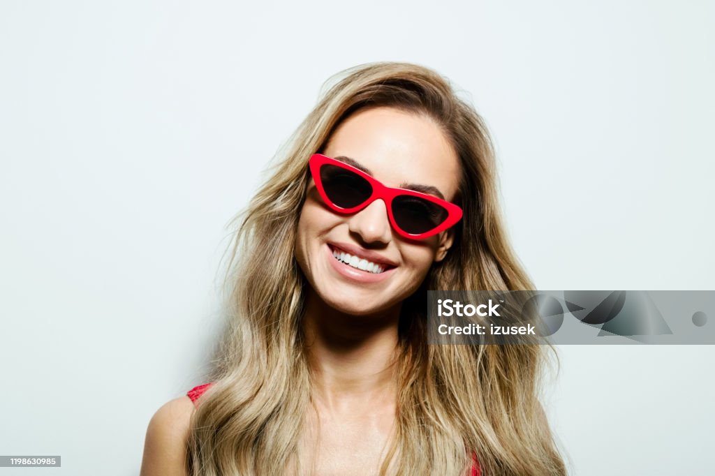 Summer portrait of young woman Portrait of happy beautiful long hair young woman wearing red sunglasses, smiling at camera. Studio shot on white background. 25-29 Years Stock Photo