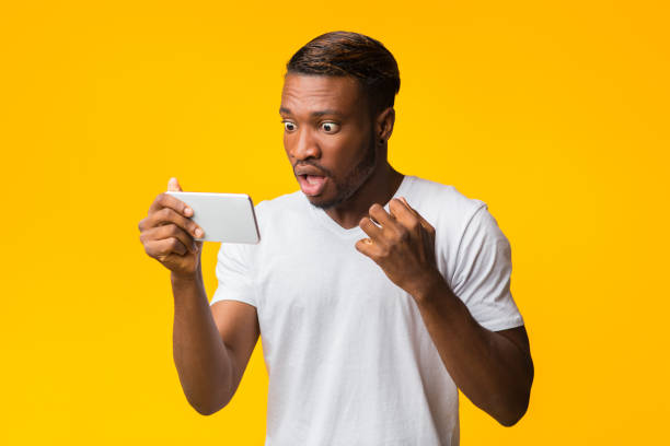 istock Shocked Afro Guy Looking At Smartphone Standing In Studio 1198633439