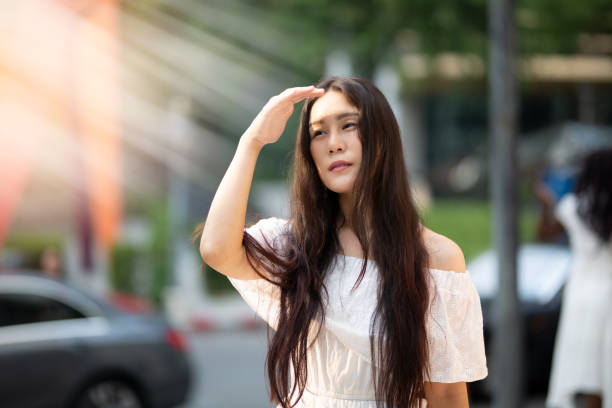 istock Young Woman Shielding Eyes While Standing On Road 1198633602
