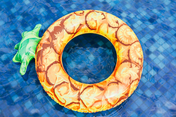 ananas-pool-float, ring schwimmend in einem erfrischenden blauen pool - swimming pool inner tube toy float stock-fotos und bilder