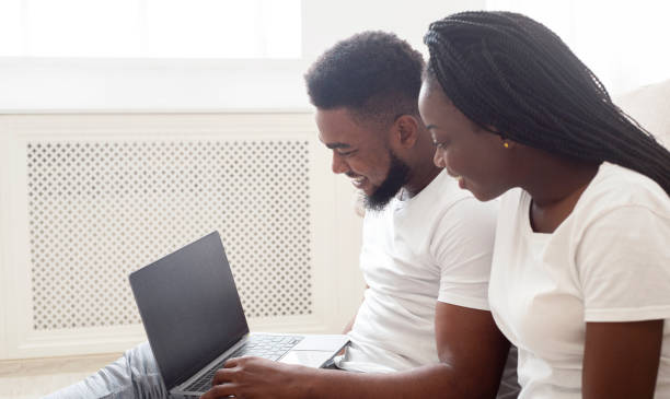 istock Young black couple using laptop with black screen at home 1198637332