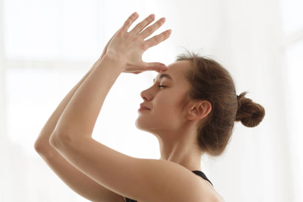 istock Girl doing meditating exercise with hands together on forehead 1198637414