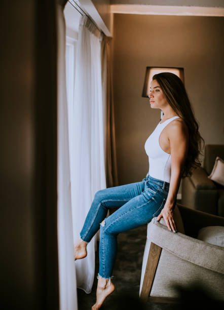 istock Beautiful young woman sitting by the window 1198638671