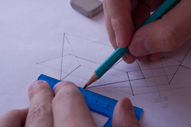 istock A man draws a diagram with a ruler, eraser and pencil. Design and create a project on a white sheet of paper close-up. 1198638936