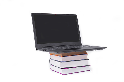 Modern slim laptop on a pile of books