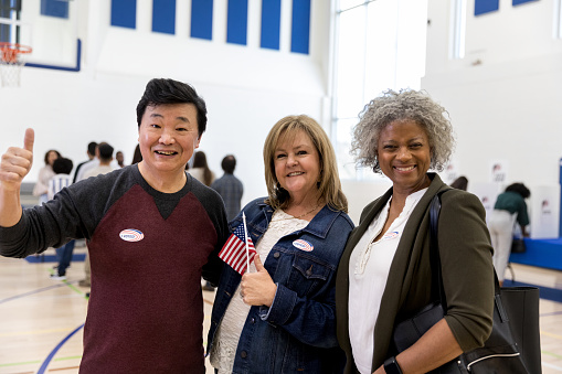 Giving a thumbs up, the three mature adults are happy after voting.