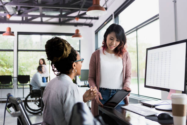 istock Mid adult female looks at tablet while co-worker speaks 1198645742
