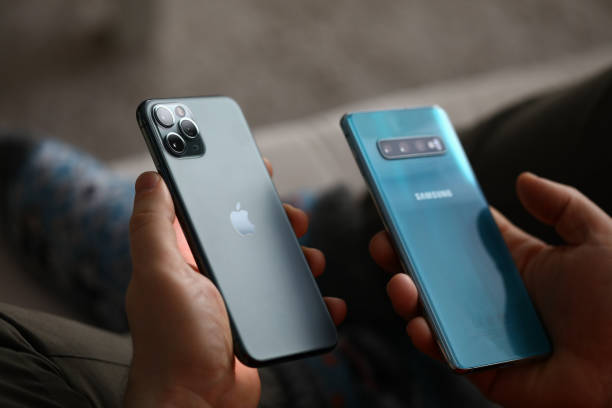 männliche hand halten apple iphone pro und samsung galaxy s 10 - samsung group fotos stock-fotos und bilder