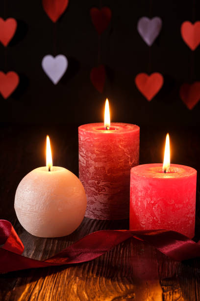 istock Three wax flame candlelight with ribbon in dark romantic light on hearts background, love dating, Valentine's day, selective focus 1198646419
