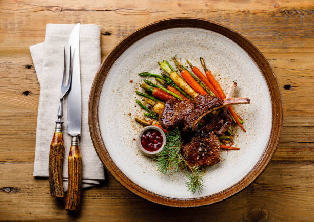 grilled venison ribs with baked vegetables and berry sauce on wooden background - venison imagens e fotografias de stock