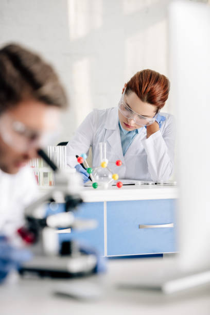 istock selective focus of genetic consultant writing and colleague using microscope in lab 1198646656