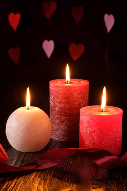 istock Three wax flame candlelight with ribbon in dark romantic light on hearts background, love dating, Valentine's day, selective focus 1198647540