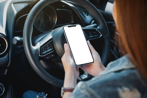 a woman holding and using mobile phone with blank screen while driving car stock photo