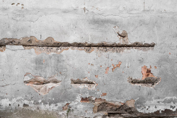 istock Cracked concrete grey wall covered with gray cement texture as background can be used in design. Dirty concrete texture with cracks and holes. 1198648957