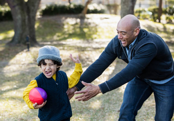 istock Hispanic boy and father playing with football 1198650188