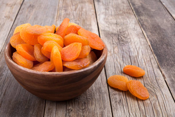 fruits secs avec des noix dans le bol en bois - dried apricot photos et images de collection