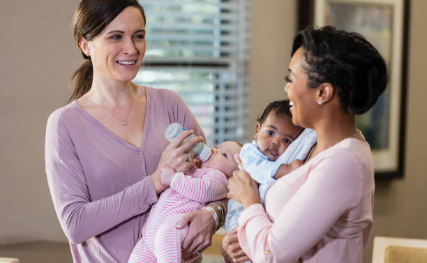 istock Two mothers with their babies, holding and feeding 1198650769