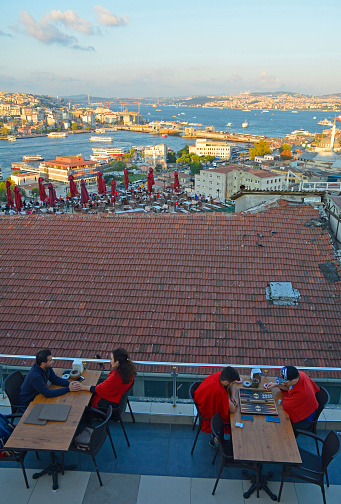 Istanbul, Turkey - September 7th 2019. Customers at a rooftop bar enjoy a panorama view of Istanbul from close to Suleymaniye mosque in Eminonu, Fatih. It shows the view across the Bosphorus towards Karakoy in Beyoglu, with the Galata Bridge in the centre distance and Uskudar in the background