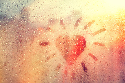 speech buble heart like sun on foggy window spattered with drops city, yellow red color, copyspace