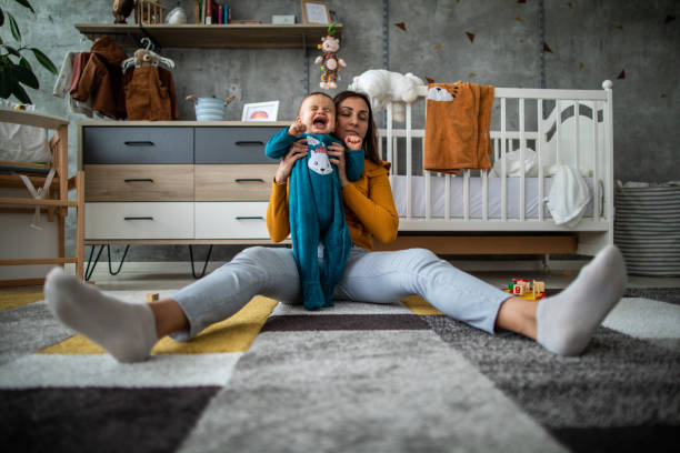 istock Baby boy in pajamas crying while mother holding him 1198664582