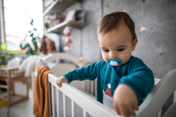 istock Toddler boy with pacifier standing in his crib 1198665663
