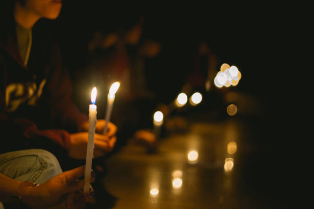 people lighting candle vigil in darkness seeking hope, worship, prayer soft focus of people lighting candle vigil in darkness seeking hope, worship, prayer church like a holy light from god stock pictures, royalty-free photos & images