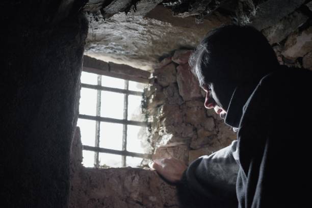 istock Man prisoner or captive in the dark underground cell 1198680266