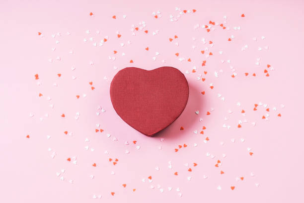 istock Present box heart on pastel pink background with multicolored confetti Flat lay 1198681858
