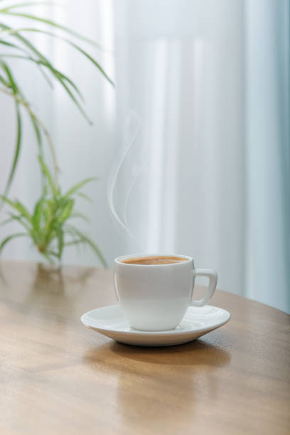istock Fresh aromatic coffee in a white ceramic cup on a wooden table. Light background. 1198682715