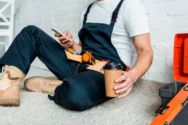 istock cropped view of installer sitting on carpet while holding paper cup and using smartphone 1198682805