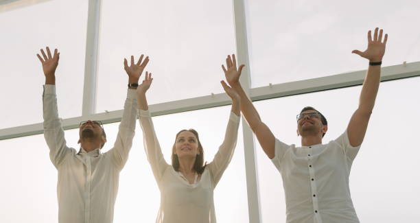 istock successful business team stands with hands up. 1198683661
